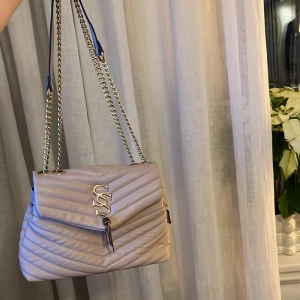 Beige quiltad axelväska med kedjedetaljer - Snygg beige axelväska med quiltad design och kedjedetaljer. Ysl inspo (fransarna som hänger har rostat men man kan enkelt fixa eller ta bort dom)