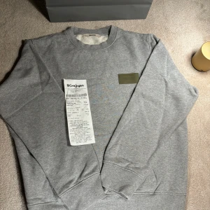 Grå sweatshirt från Zadig & Voltaire - Säljer en stilren nästan helt ny sweatshirt från Zadig & Voltaire. Tröjan har en rund halsringning och en snygg patchdetalj på bröstet. Perfekt för en avslappnad look. Kvitto finns 
