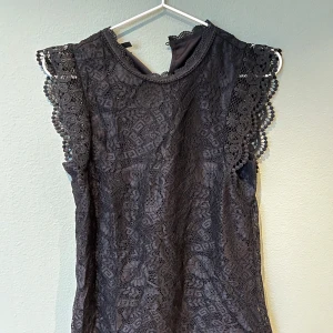 Svart spetsblus från Pieces - Elegant svart spetsblus från Pieces med vackra detaljer. Blusen är ärmlös och har en rund halsringning med spets💕 Storlek XS