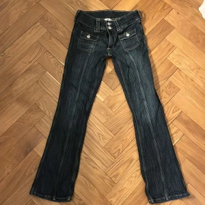 Blå  lågmidjade bootcut jeans från H&M - Snygga blå bootcut jeans från H&M med låg midja och justerbar midja. De har två framfickor med knappar och en klassisk femficksdesign. Säljer då de är lite för små.