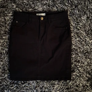 svart jeanskjol - Svart jeanskjol från cubus i storlek 36. Sparsamt använd. liten slits där bak.