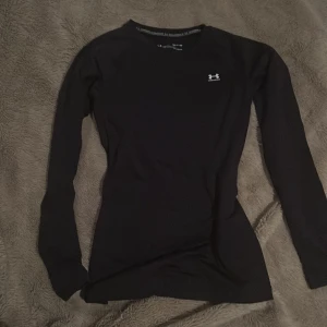 Svart långärmad tröja från Under Armour - Säljer en svart långärmad tröja från Under Armour i mycket bra skick. Perfekt för kalla dagar med ColdGear-teknologi som håller dig varm. Tröjan är tight och har en liten logga på bröstet. Passar perfekt för träning eller som baslager under vintern. 🖤 passar mellan xs-m. Använd kanske 2 gånger max.