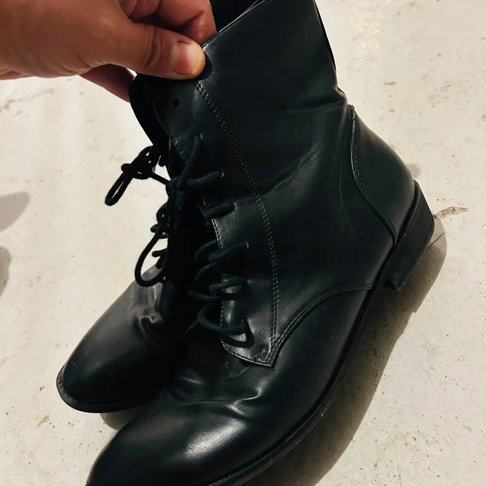 Säljer ett par svarta boots i skinn från H&M Divided. De har en klassisk design med snörning framtill och är i mycket bra skick. Perfekta för höst och vinter, och passar både till vardags och lite mer uppklädda tillfällen.. Skor.