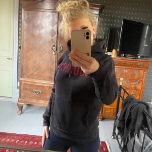 Svart hoodie från Hoodrich - Säljer en svart hoodie från Hoodrich. Den har en stor röd logga på bröstet och en praktisk magficka. Perfekt för höst och vinter, och den är supermysig att ha på sig. Passar både till vardags och chillkvällar. Loggan där framme är som knaprig men inget man tänker på när man har på sig den. Färgen är lite avtvättad. Hör av dig om du är intresserad! 