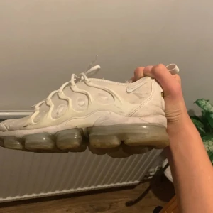 Vita Nike Vapormax sneakers - Säljer ett par vita Nike Vapormax sneakers i bra skick. De har en unik bubbelsula och klassisk snörning. Perfekta för både träning och vardagsbruk. Lite smutsiga men kan enkelt rengöras för att se fräscha ut igen. En pumpa i skon är sönder o riv märken 