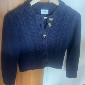 Mörkblå stickad kofta från Boomerang - Säljer en snygg mörkblå stickad kofta från Boomerang i storlek M. Den har ett flätmönster framtill och sex stora knappar. Perfekt för höst och vinter, och den är supermysig att ha på sig. Passar både till vardags och lite finare tillfällen. 🧶💙