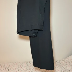 Svarta kostymbyxor - Snygga svarta kostymbyxor i klassisk stil. Perfekta för både kontoret och festliga tillfällen. De har en rak passform och är tillverkade i ett bekvämt material som ger en stilren look. Ett måste i garderoben för en elegant och tidlös stil. Jag anser att de är mer 36 än 38 i storlek! 