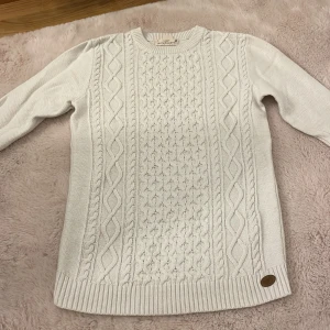 Vit stickad tröja från L.O.G.G. - Säljer en superfin vit stickad tröja från L.O.G.G. (H&M) i storlek M. Den har ett snyggt flätmönster på framsidan och är perfekt inför hösten/vintern. Tröjan är i okej skick då den har en liten fläck på framsidan, som man förmodligen kan få bort med produkter.