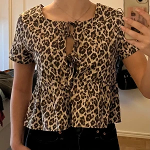 Leopardmönstrad blus med knytning - Säljer en superfin leopardmönstrad blus med korta ärmar och knytning framtill. Använd ca två gånger så nästan helt ny