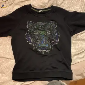 Säljer en svart sweatshirt från Kenzo med ett coolt tigerbroderi på framsidan. Tröjan har en normal passform och är perfekt för både höst och vinter. Den är i mycket bra skick och gjord av mjukt bomullsmaterial. Perfekt för att ge din outfit en edgy touch! Byter gärna mot något annat så som dsq2 jeans i svart eller något annat 