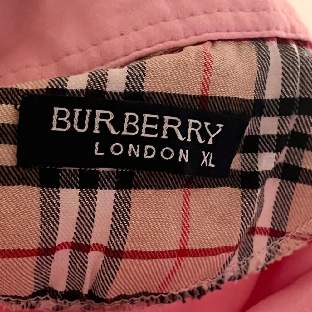 Säljer en snygg rosa kortärmad topp från Burberry i storlek XL i barn storlek . Den har en klassisk krage med Burberrys ikoniska rutiga mönster på insidan. Perfekt för en stilren och avslappnad look. Passar både till vardags och fest!. Toppar.