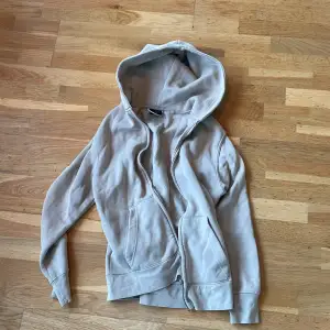 Säljer en snygg beige hoodie från Pull&Bear i storlek XS. Den har en dragkedja framtill och en mysig huva. Perfekt för en avslappnad stil och passar bra till både jeans och leggings. Använd men i bra skick! Nypris 400:-