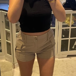 Beige shorts med fickor - Säljer ett par snygga beige shorts i mycket bra skick. De har en bekväm passform med elastisk midja och praktiska fickor på sidorna. Storlek S men små i storleken❤️