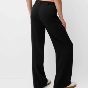 Svarta kostymbyxor från Bershka - Snygga svarta kostymbyxor från Bershka i storlek S. Elegant wide fit som ger en stilren look och i mjukt material som gör att de både är bekväma och snygga!  Bild 2 och 3 är mina egna bilder, övriga två är produktbilder på likadana byxor som mina. 