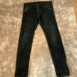 Mörkblåa Dsquared2 jeans, storlek 48 - Snygga jeans från Dsquared2 med en slim fit. De har en mörkblå färg och en distinkt stil. Jeansen har inga deffekter och har inte använts mycket alls,   Måtten är:   Midjevidd: 45 cm  Yttre benlängd: 110 cm   Inre benlängd: cirka 83 cm