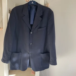 Svart kavaj från Hugo Boss - Säljer en stilren svart kavaj från Hugo Boss. Kavajen har en klassisk design med tre knappar framtill och två fickor. Perfekt för både formella och semi-formella tillfällen. Den är i bra skick . Storlek står inte men tror det är Lars . Måttet från ax