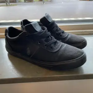 Säljer ett par svarta sneakers från Polo. De är i bra skick och har en stilren design med snörning. Perfekta för vardagsbruk och passar till det mesta. Skorna har en diskret logga på sidan och är gjorda i ett slitstarkt material.