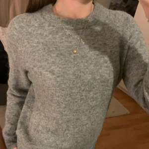 Grå stickad tröja från Zara - Säljer en supermysig grå stickad tröja från Zara. Perfekt för kyliga dagar med sin mjuka och varma känsla. Tröjan har en klassisk design med långa ärmar och rund halsringning. Passar perfekt till både jeans och kjol för en avslappnad look. 🩶