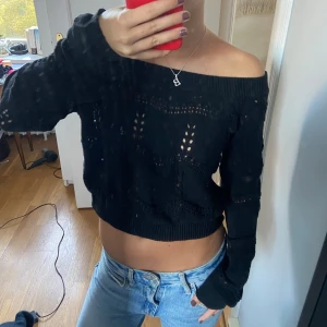 Svart stickad offshoulder-tröja - Säljer en superfin svart stickad tröja med offshoulder-design. Den är croppad och har långa ärmar. Tröjan har ett snyggt hålmönster!! Perfekt nu till hösten