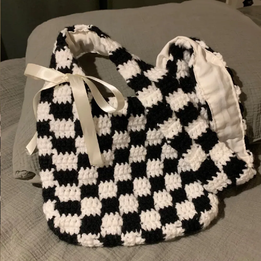 Handmade crochet bag, crocheted by hand with black and white acrylic yarn in a checkered pattern. The bag has a sewn in lining which provides extra item durability and security for the items inside :) width: 24 cm height: 21 cm strap length: 85.5 cm. Väskor.