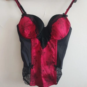 korsett topp - En superfin svart och röd korsett med mönster. Korsetten är storlek 80B men passar S/M. Den går även att justera med spännerna bak💕Priset går att diskutera 