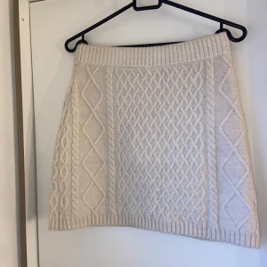 Créme/vit stickad kjol - Kort stickad kjol ifrån H&M. Använd ett fåtal gånger utan defekter. Cremefärgad/beige/vit i storlek xs men väldigt stretchigt material