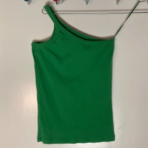 Enarmat asymmetrisk grönt linne - Snyggt enarmat asymmetrisk grönt linne i stretchigt ribbad material  Storlek S