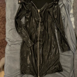 Svart skinnjacka med dragkedja - Säljer en svart läder klänning med cool dragkedja framtill. klänningen har långa ärmar och en snygg, glansig finish.