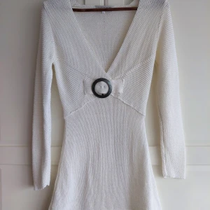 Vit stickad tröja/tunika med v-ringning Joachim Bosse - Säljer en superfin vit stickad tröja/tunika med v-ringning och långärmade ärmar. Den har en snygg detalj med en stor ring i midjan som ger en unik touch. Sömmen har spruckit lite bak, men det fixar du lätt med nål&tråd 😉 Perfekt för både vardag och fest! 💫