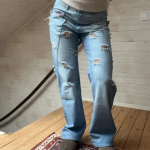 Ljusa slitna jeans - Säljer ett par ljusa jeans med slitningar för en cool och avslappnad look. De har en straight passform och är perfekta för vardagsbruk. Jeansen har flera slitna detaljer som ger dem en trendig stil.