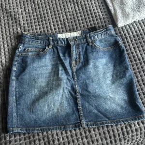 Mörk blå med oranga stygn Jeans kjol - Jeans kjol som inte är jätte hög midjas man kan kalla medel läng. 