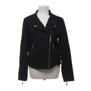 Svart jacka från KappAhl - Säljer en snygg svart jacka från KappAhl. Den har en cool asymmetrisk dragkedja framtill och två fickor med dragkedjor. Jackan är långärmad och har en stilren design med små detaljer i guld. Perfekt för höst och vår!