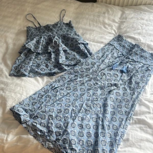 Ett sätt med en lång kjol och en topp/linne med volanger. Aldrig använt. Fin blå färg med mönster på. Kjolen har en tjock midje band med fina snören. - Aldrig använt, bra skick, skönt material