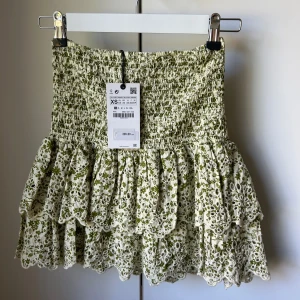 Volangkjol - En kort kjol med volanger från Zara med blommor i militärgrön färg. Aldrig använd. Storlek Xs 