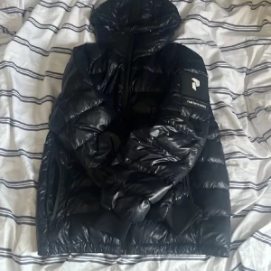 Svart pufferjacka från Peak Performance - Säljer en snygg svart pufferjacka från Peak Performance. Den är perfekt för kalla dagar. Har hål på ryggen men är inte super stort