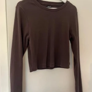 Brun croppad tröja från Gina Tricot - Säljer en brun croppad tröja från Gina Tricot. Tröjan har långa ärmar och en enkel design som passar perfekt till vardags. Perfekt för lager-på-lager under hösten.