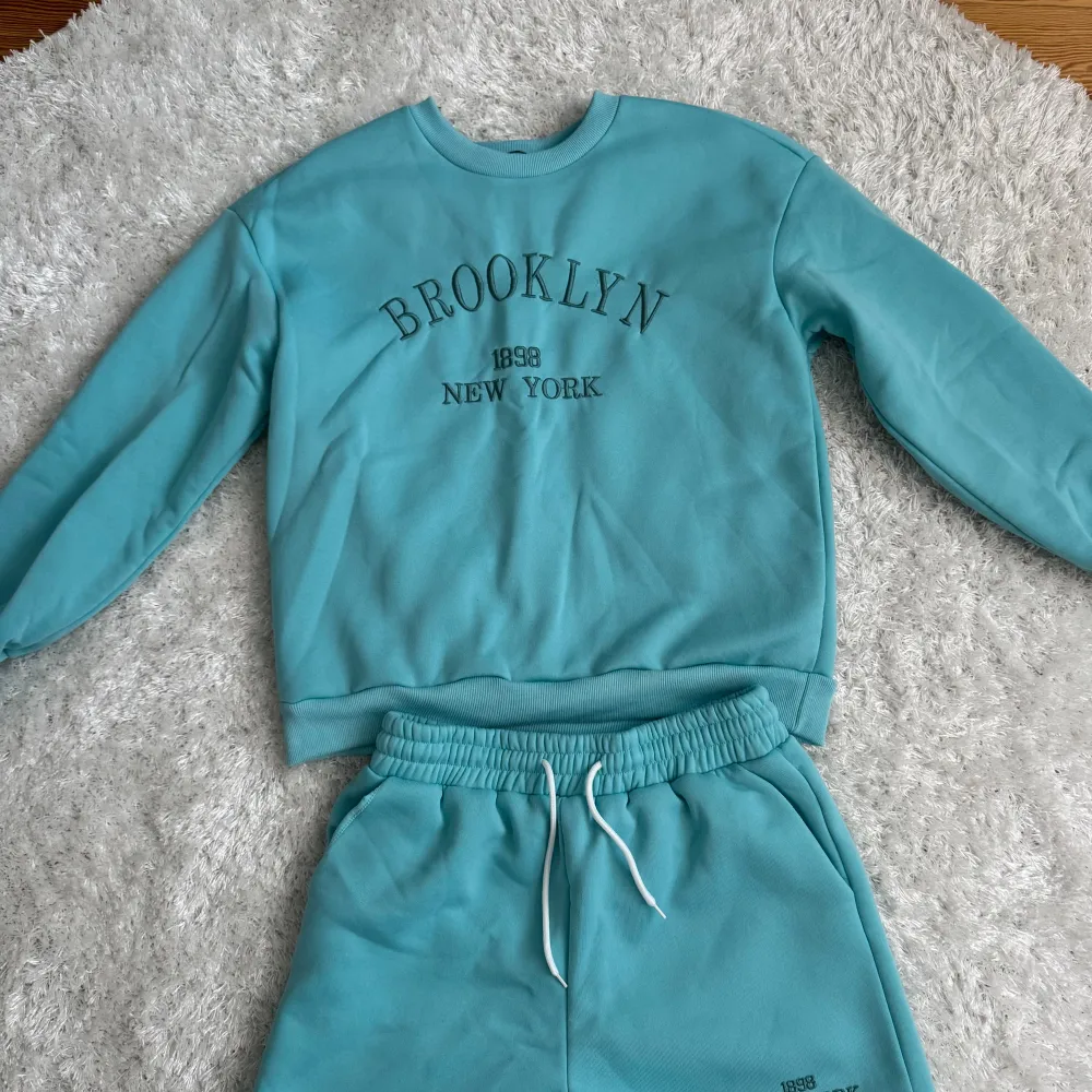 Säljer en snygg turkos sweatshirt med texten 'Brooklyn 1988 New York' tryckt på framsidan. Tröjan har långa ärmar och en rund halsringning. Perfekt för en avslappnad stil.. Neuletakit & Villapaidat.