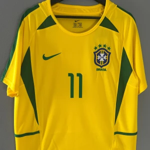 Brasiliansk fotbollströja 2002 Ronaldinho nr 11 - Fotbollströja Brasilien 2002 Ronaldinho nr 11. Helt ny med tagg. Det är en replika i storlek M Kom gärna med prisförslag!