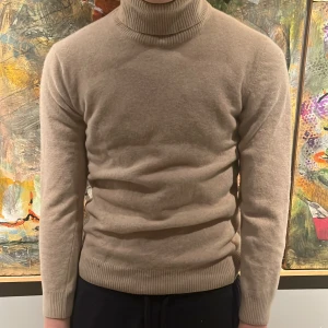 Kashmir - Säljer en stilren beige polotröja från Daniele Fiesoli. Tröjan är i ett mjukt material och har långa ärmar med ribbade muddar. Perfekt för kyligare dagar och ger en klassisk look.