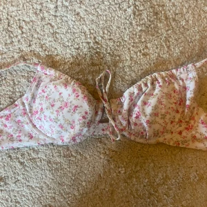 Blommig bikiniöverdel från bikbok - Söt bikiniöverdel med blommigt mönster i rosa och vitt. Den har en knytning framtill för. Perfekt för sommarens stranddagar! Köpte för 2 år sen på bik bok men har inte kommit till så mycket användning sen dess. Köpte för 260kr, säljer för 139kr ❤️I storlek s