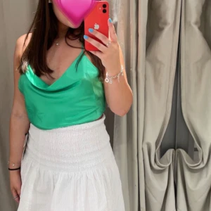 Grön satinlinne från Zara - Snygg grön satinlinne från Zara med smala axelband och draperad halsringning. Toppen är croppad och har en öppen rygg med knytband. Perfekt för en somrig look! Använd 1-2 gånger och är i därför mycket bra skick!