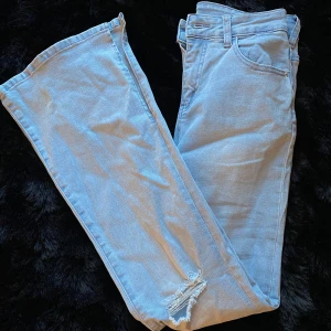 Ljusblå jeans med slitningar - Snygga ljusblå jeans med bootcut-stil och slitningar på knäna. Perfekta för en avslappnad look. De har en hög midja och klassisk femficksdesign.