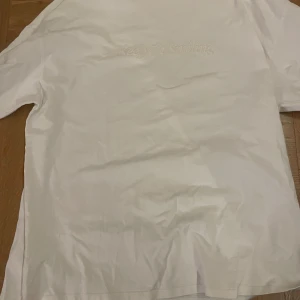 Vit t-shirt med text - Säljer en vit t-shirt med texten 'Keep on Smiling' tryckt på framsidan. T-shirten har en normal passform och korta ärmar, perfekt för en avslappnad stil.