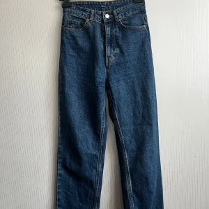 Blå jeans från Monki - Snygga blå jeans från Monki med klassisk femficksdesign och knappgylf. De har en hög midja och raka ben, vilket ger en tidlös look. Perfekta för en avslappnad stil.
