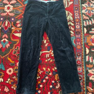 Mörkblå manchesterbyxor från Ralph Lauren - Snygga mörkblå manchesterbyxor från Ralph Lauren med broderad logga i rött. Byxorna har en klassisk rak passform och är perfekta för en stilren look. De har knappar och bälteshällor för extra stil och funktion.