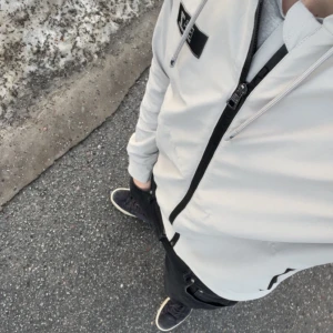 Vit jacka från Emporio Armani - Säljer en stilren vit jacka från Emporio Armani med svart dragkedja och EA7-logga på bröstet. Perfekt för en modern look. Jackan har långa ärmar och en snygg passform. Ny pris 1650 pris kan ändras vid snabb affär 