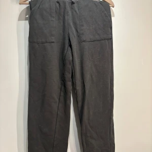 Svarta mjukisbyxor med snörning - Säljer ett par svarta mjukisbyxor med bekväm passform och praktisk snörning i midjan. Byxorna har stora fickor framtill och är perfekta för en avslappnad stil. Perfekta för mysiga dagar hemma eller en avslappnad dag ute.