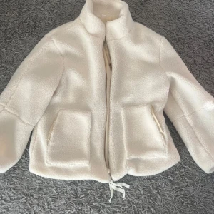 Vit teddyjacka med dragkedja - Mysig vit teddyjacka med dragkedja och två stora fickor där fram. Säljer vidare från en annan plick användare då denna var för liten på mig. 😢