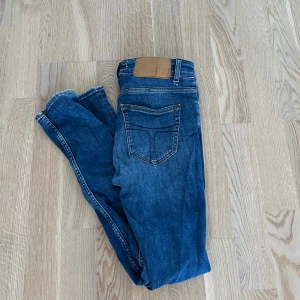 Blå jeans - Ett par marinblå tiger of sweden jeans i helt okej skick pågrund av att det är ett hål i en av bält hängslerna.