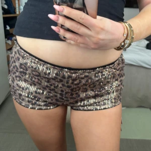 Glittriga leopardmönstrade shorts - Snygga shorts med leopardmönster och glittriga paljetter. Perfekta för att sticka ut på festen. De har en tight passform och låg midja, vilket ger en trendig look.
